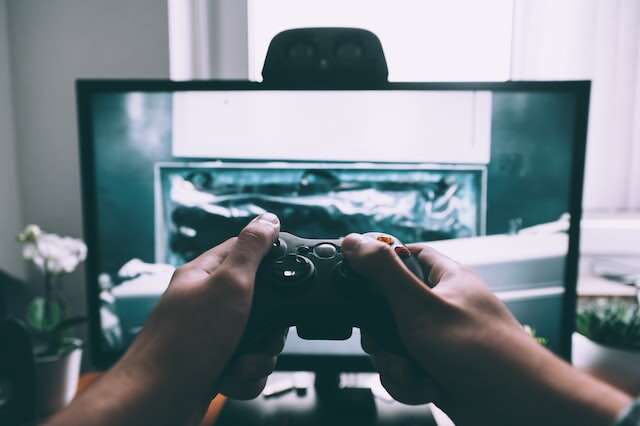 gracz trzymający w rękach pada przed telewizorem
